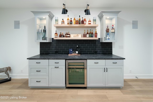 bar featuring wine cooler, backsplash, white cabinetry, and light hardwood / wood-style floors