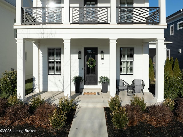 view of exterior entry featuring a porch and a balcony