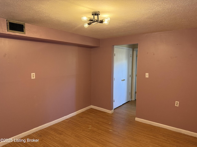 spare room featuring wood-type flooring and a textured ceiling