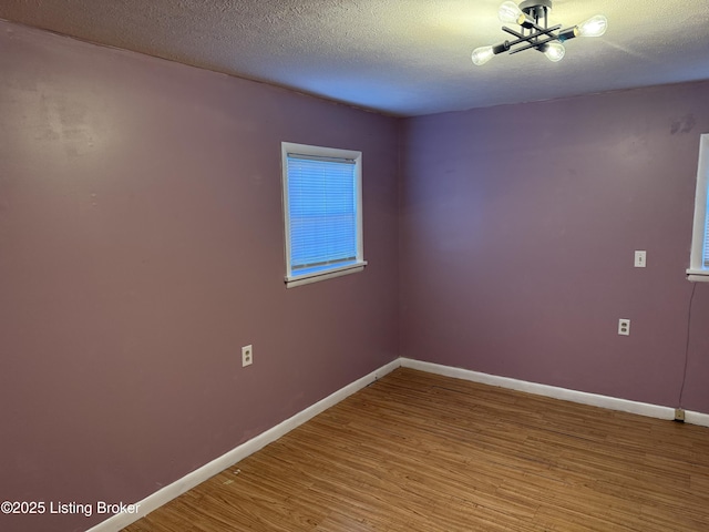 unfurnished room with hardwood / wood-style floors and a textured ceiling