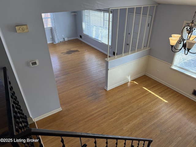 interior space featuring wood-type flooring, a healthy amount of sunlight, and a chandelier