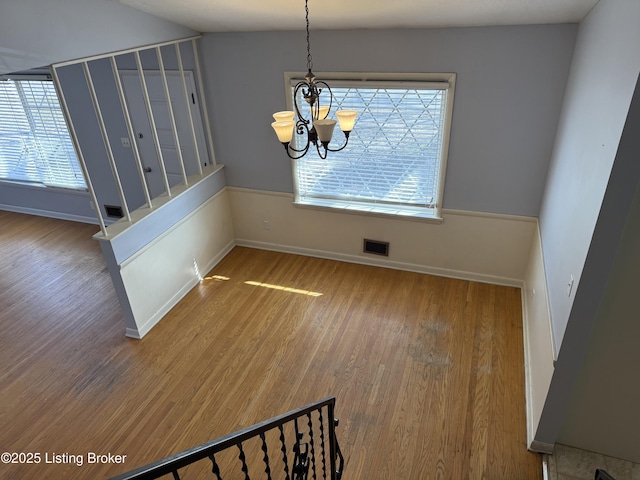 dining space with an inviting chandelier, a healthy amount of sunlight, and hardwood / wood-style flooring