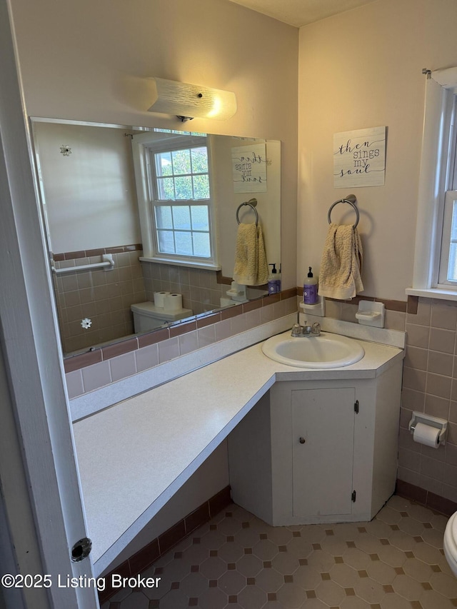 bathroom featuring vanity, tile walls, and toilet