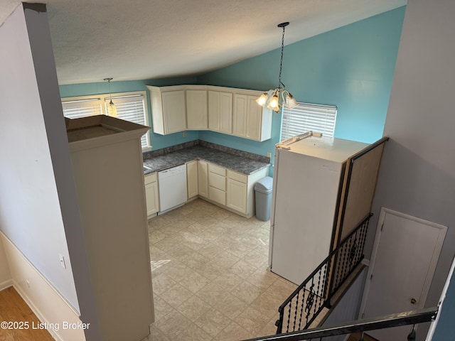 kitchen with decorative light fixtures, lofted ceiling, white dishwasher, cream cabinets, and an inviting chandelier