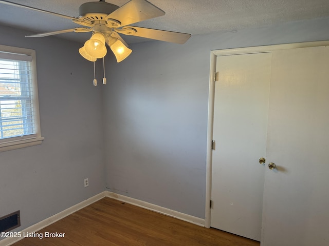 empty room with wood-type flooring, ceiling fan, and a textured ceiling