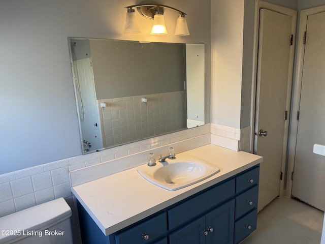 bathroom with vanity, tile walls, and toilet