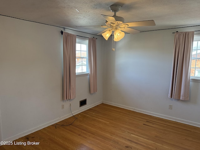 unfurnished room with ceiling fan, a wealth of natural light, a textured ceiling, and light wood-type flooring