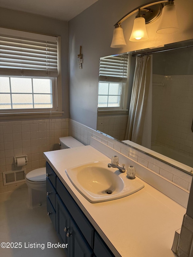 bathroom featuring tile patterned flooring, plenty of natural light, tile walls, and toilet