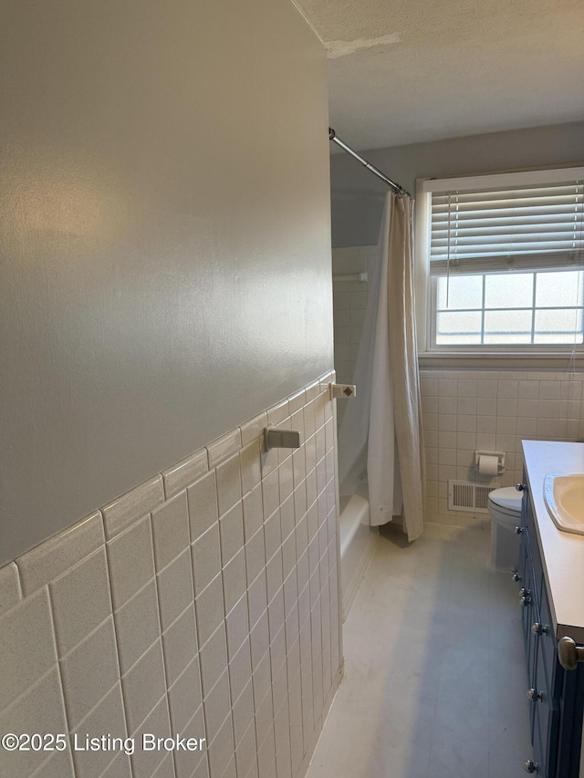 full bathroom with shower / bathtub combination with curtain, vanity, toilet, and tile walls