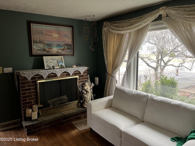 living room featuring a brick fireplace, dark hardwood / wood-style floors, and a textured ceiling