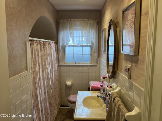 bathroom featuring vanity, toilet, and tile walls