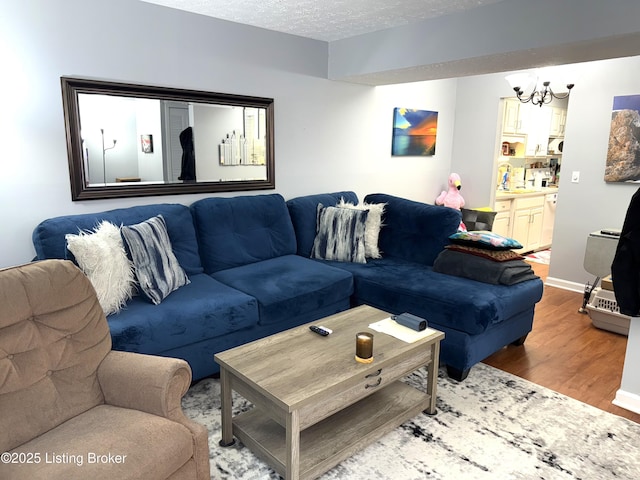 living room featuring an inviting chandelier, wood-type flooring, and a textured ceiling