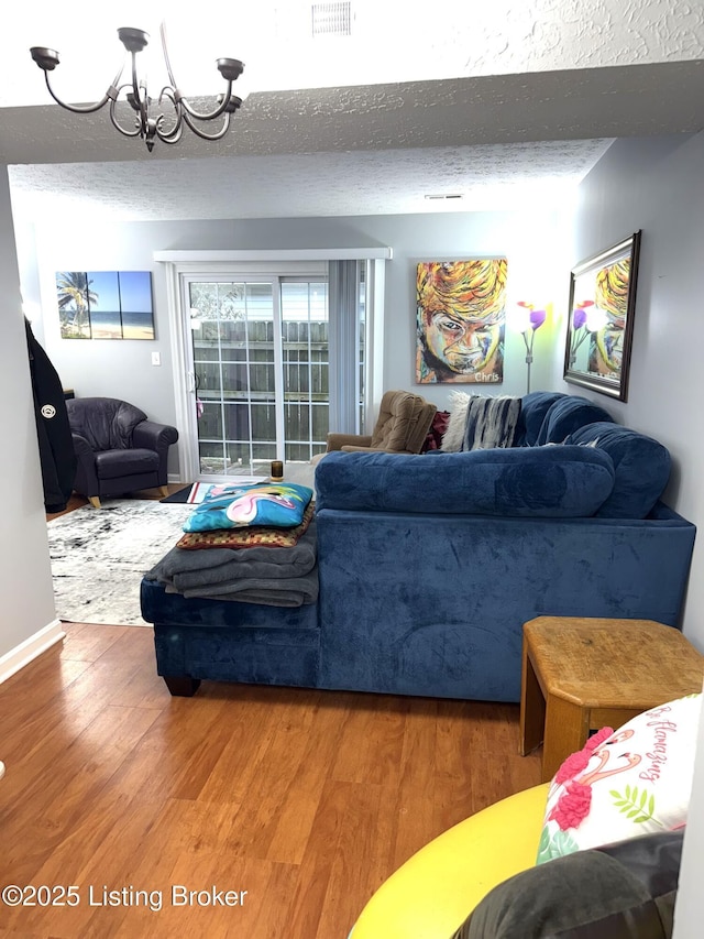 living room featuring an inviting chandelier, wood-type flooring, and a textured ceiling