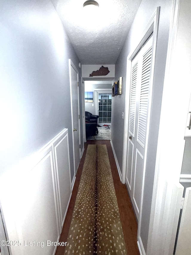 hall featuring dark hardwood / wood-style floors and a textured ceiling