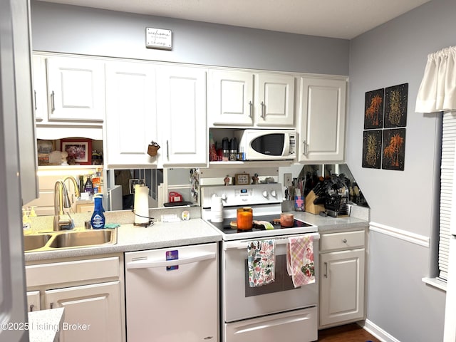 kitchen featuring white cabinetry, sink, and white appliances