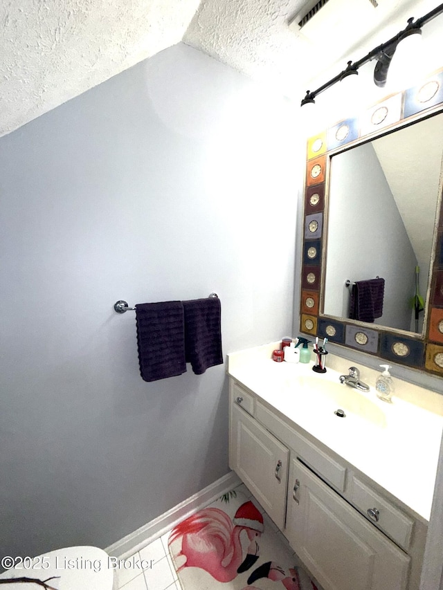 bathroom featuring tile patterned flooring, vanity, vaulted ceiling, and a textured ceiling