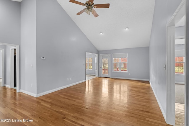 unfurnished living room with ceiling fan, high vaulted ceiling, a wealth of natural light, and light hardwood / wood-style floors