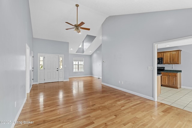 unfurnished living room featuring high vaulted ceiling, light hardwood / wood-style floors, and ceiling fan