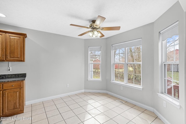 unfurnished dining area featuring light tile patterned flooring, ceiling fan, and a textured ceiling