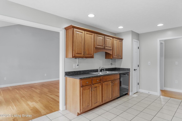 kitchen featuring sink, dark stone counters, dishwasher, and light tile patterned flooring