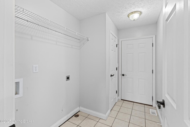 laundry area with light tile patterned floors, a textured ceiling, and electric dryer hookup