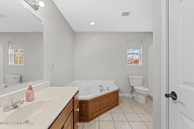 bathroom featuring tile patterned flooring, vanity, toilet, and a tub to relax in