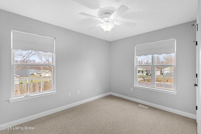 unfurnished room with a healthy amount of sunlight, ceiling fan, and carpet flooring