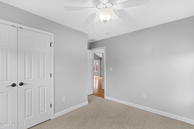 unfurnished bedroom with ceiling fan, light colored carpet, and a closet