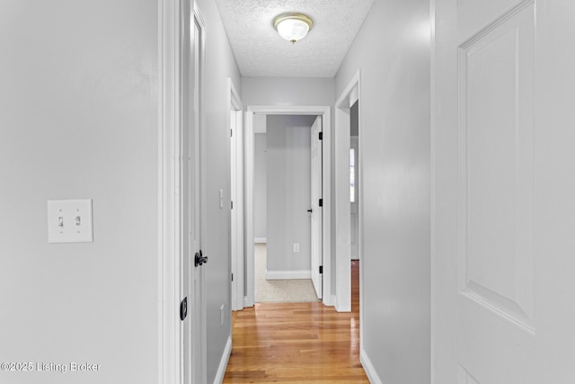 hall featuring a textured ceiling and light wood-type flooring