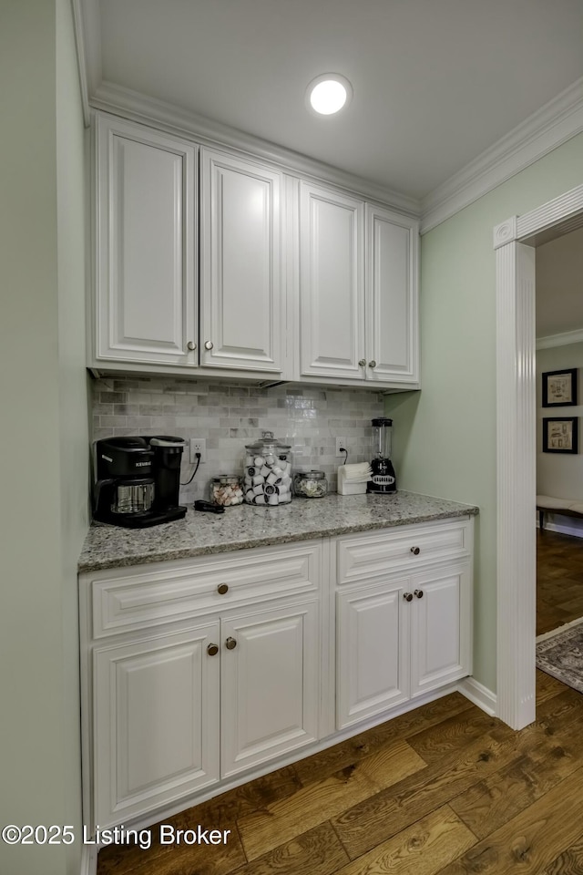 bar featuring decorative backsplash, ornamental molding, dark hardwood / wood-style floors, and white cabinets