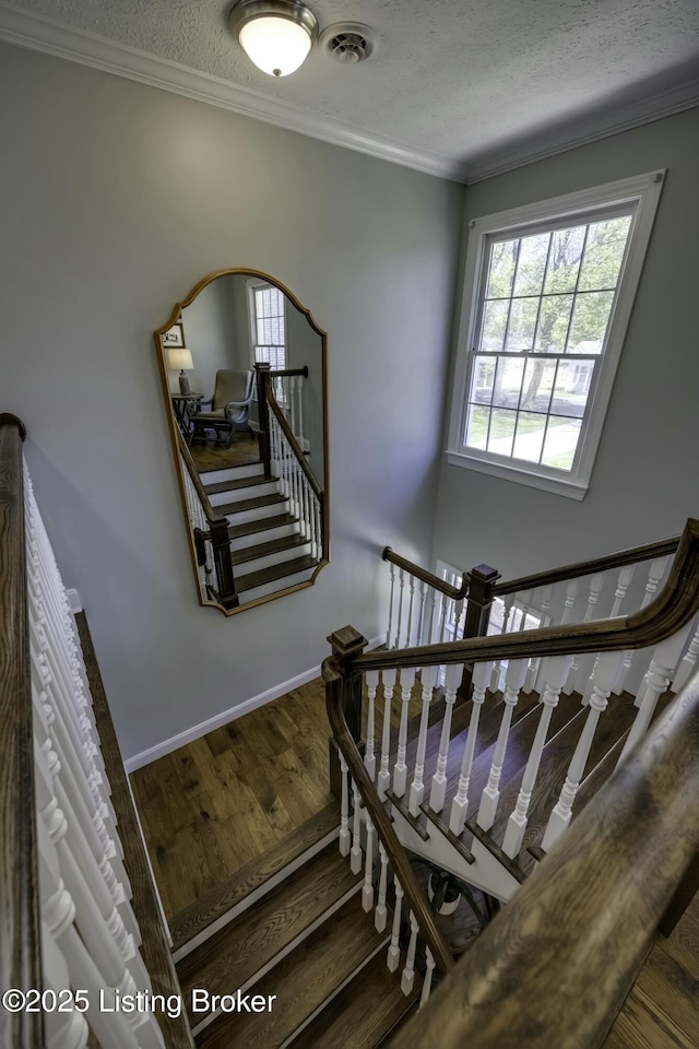 stairway with hardwood / wood-style floors, crown molding, and a textured ceiling