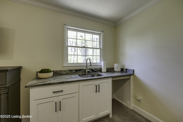 kitchen featuring sink, crown molding, white cabinetry, dark stone countertops, and dark colored carpet