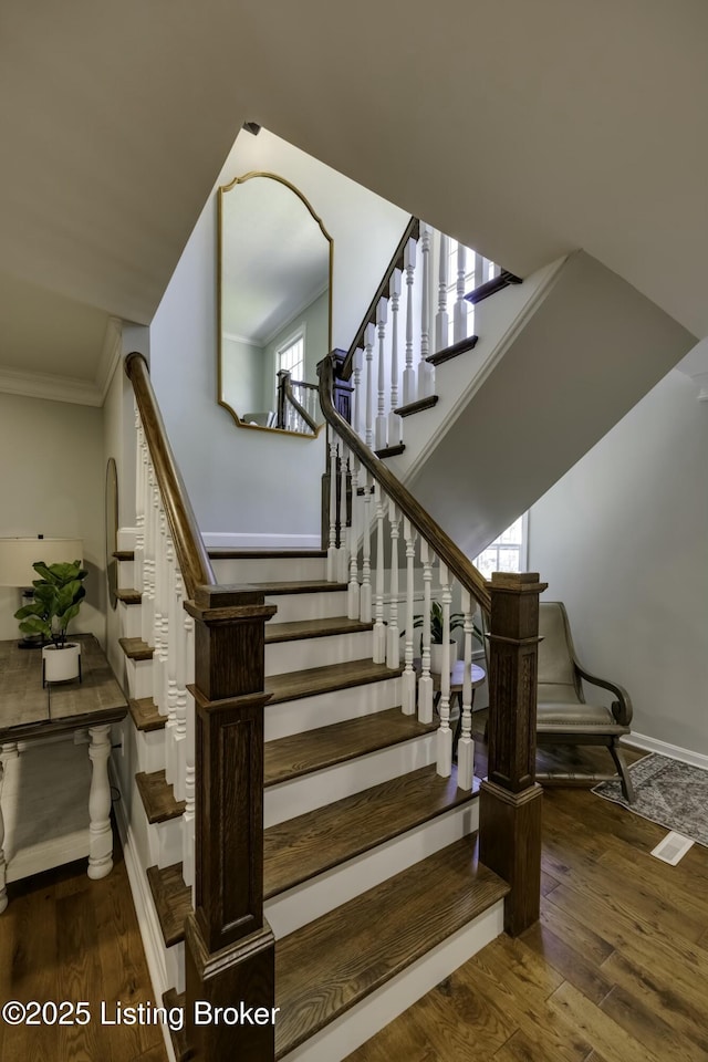 stairs featuring hardwood / wood-style floors and ornamental molding