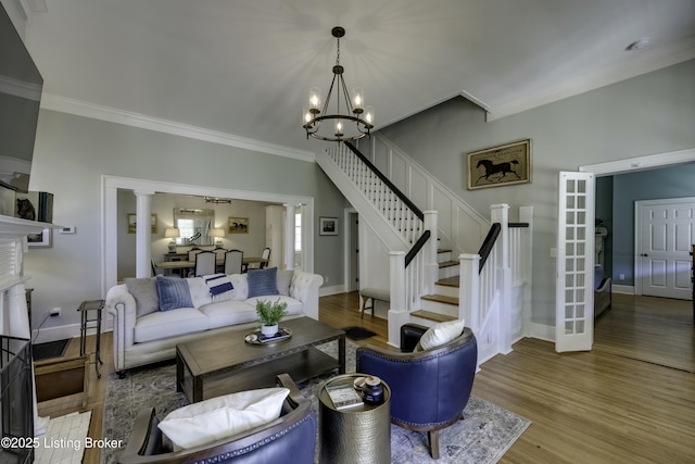 living room with an inviting chandelier, ornamental molding, light hardwood / wood-style floors, and decorative columns