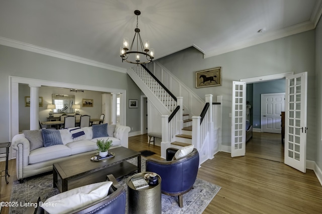 living room featuring wood-type flooring, ornamental molding, a chandelier, and french doors