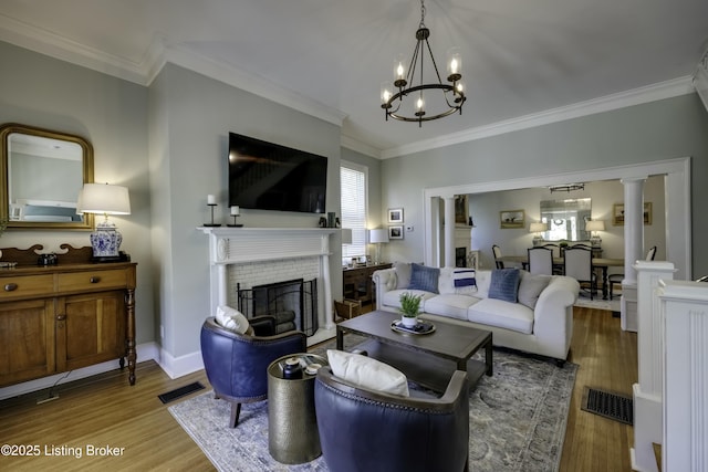 living room featuring light hardwood / wood-style flooring, a notable chandelier, a fireplace, and ornamental molding