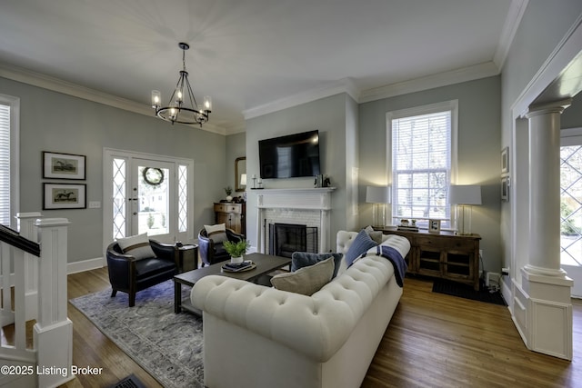 living room featuring crown molding, hardwood / wood-style floors, a brick fireplace, and ornate columns