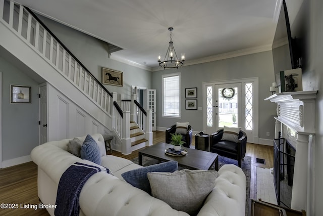 living room with dark hardwood / wood-style flooring, a notable chandelier, and ornamental molding