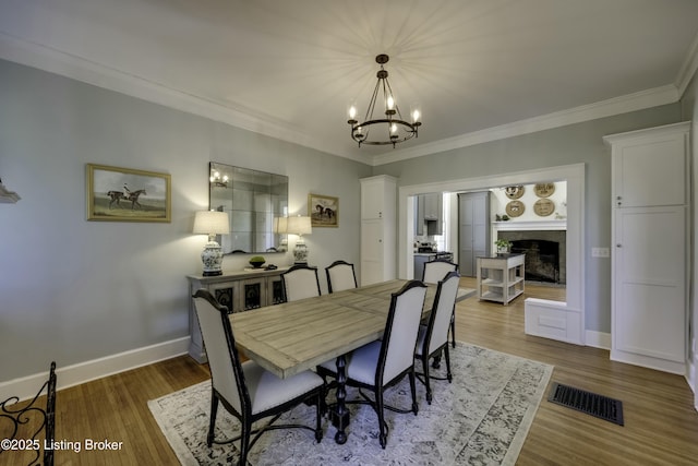 dining area featuring ornamental molding, hardwood / wood-style floors, and a notable chandelier