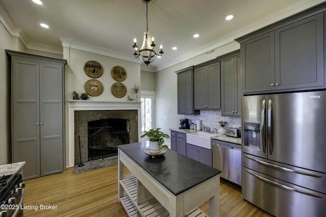 kitchen featuring pendant lighting, sink, appliances with stainless steel finishes, gray cabinetry, and a fireplace