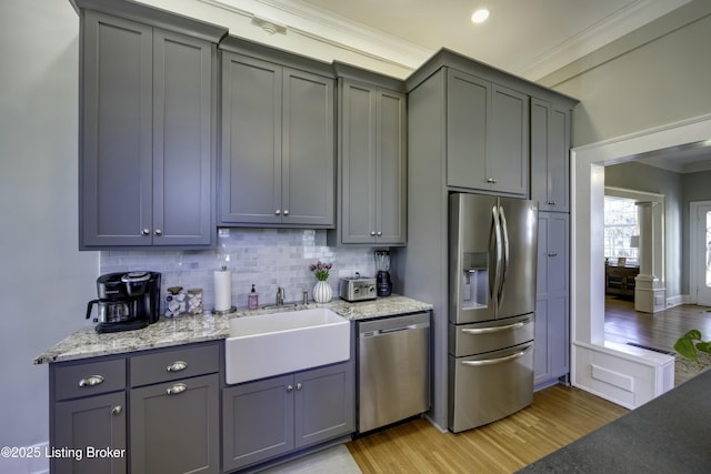 kitchen with sink, crown molding, light hardwood / wood-style flooring, gray cabinets, and stainless steel appliances