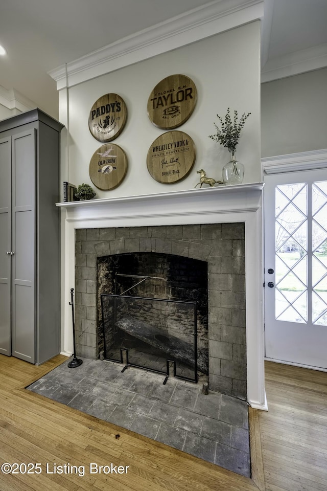 room details with a tiled fireplace, crown molding, and hardwood / wood-style flooring