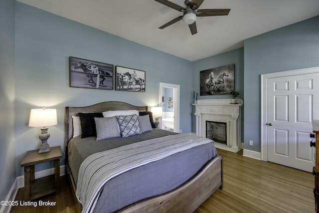 bedroom with hardwood / wood-style flooring, ceiling fan, and a brick fireplace