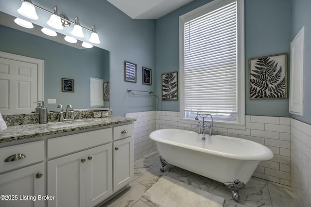 bathroom with a bathing tub, tile walls, and vanity