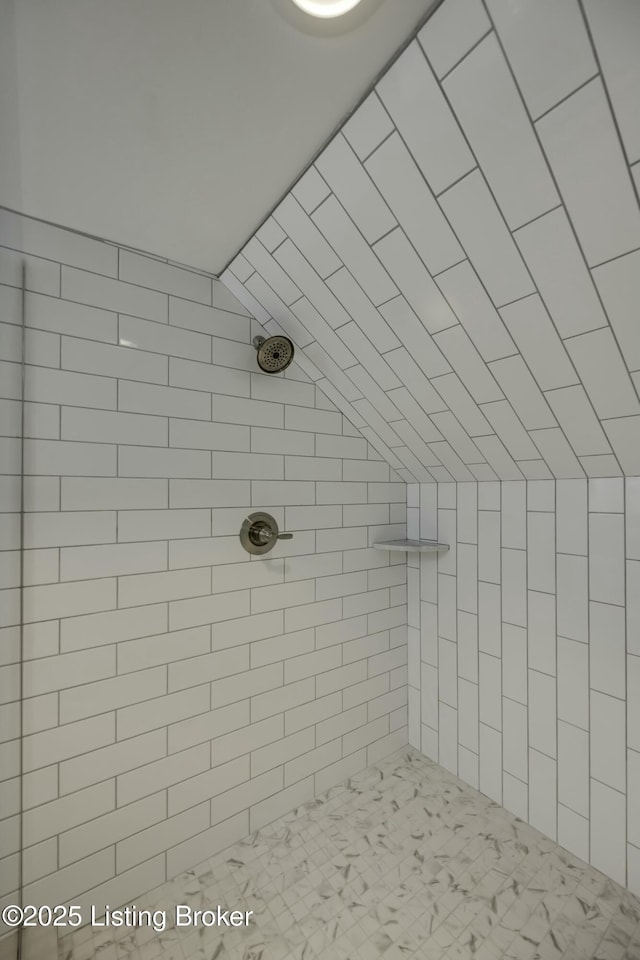 bathroom with lofted ceiling and tiled shower