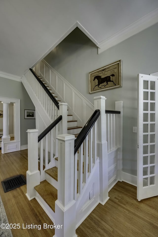 stairs featuring hardwood / wood-style floors and ornamental molding