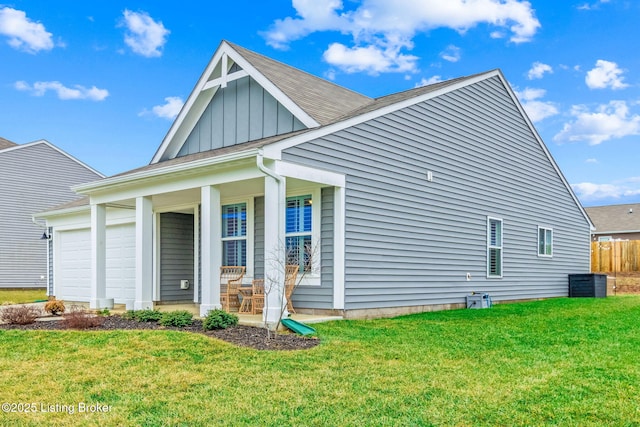 rear view of property featuring a garage, covered porch, and a lawn