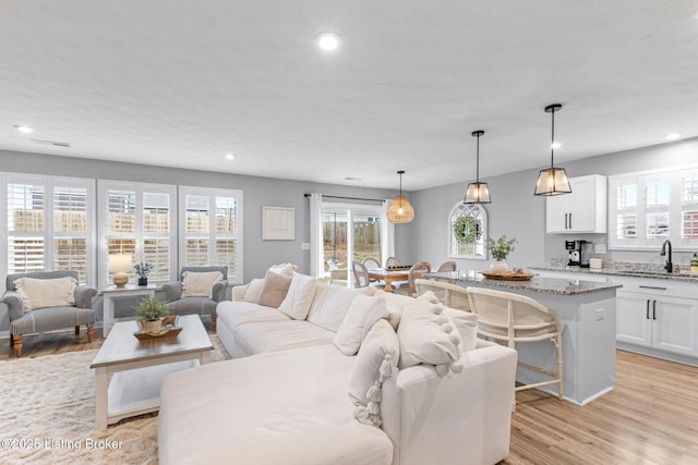 living room featuring sink, light hardwood / wood-style floors, and a textured ceiling