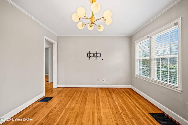 spare room with a notable chandelier, crown molding, and light hardwood / wood-style flooring