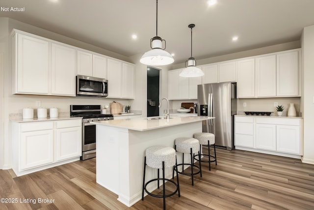 kitchen featuring stainless steel appliances, white cabinetry, and a kitchen island with sink